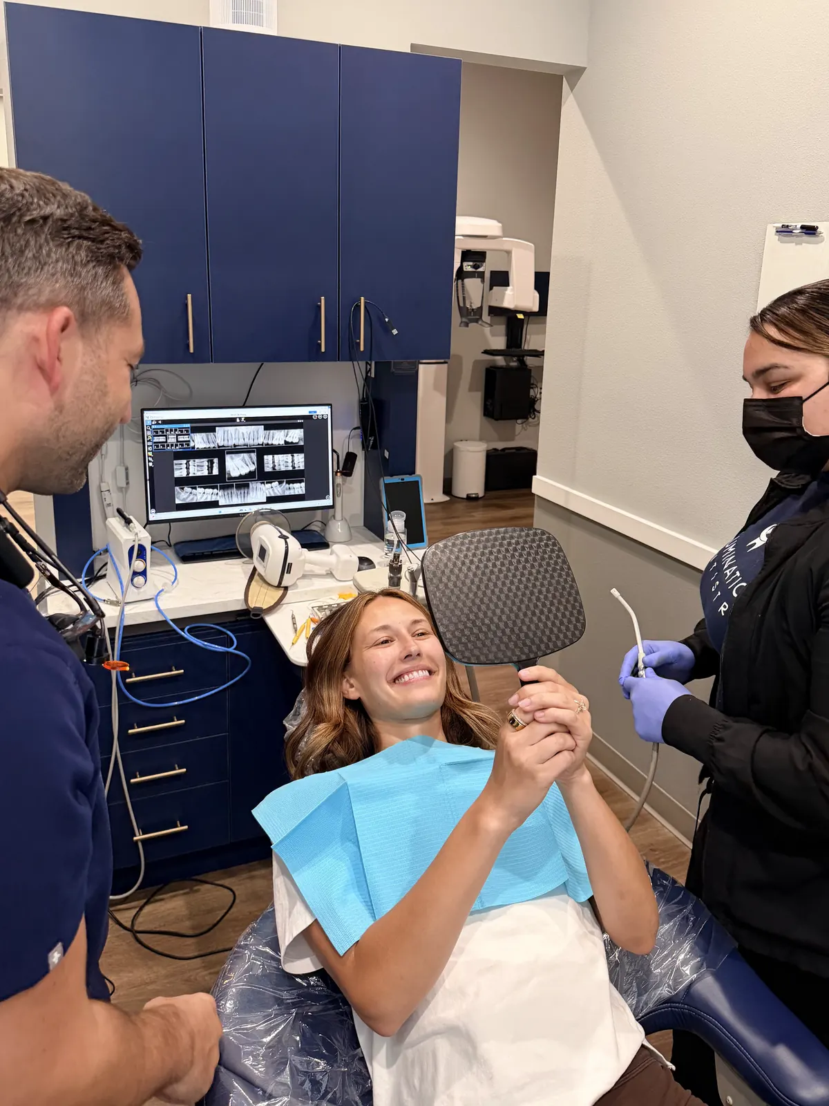 A patient smiling at her new smile in a hand mirror after treatment with Dr. Wolf and Staff 4